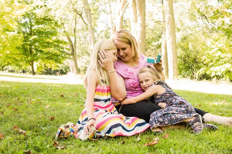 a mom cuddles with her children outside